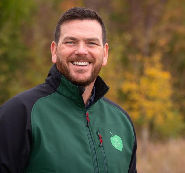 A head and shoulders shot of Andy Parsons, the charity's Chief Executive, standing smiling at the camera with autumnal trees behind him