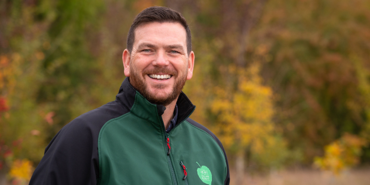 Andy Parsons, Chief Executive, at the Heart of England Forest head shot smiling at the camera in branded clothing 