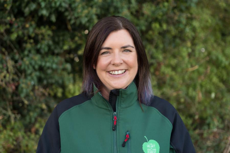 A head and shoulder shot of Claire Craige, Biodiversity Officer, standing in front of a green hedgerow