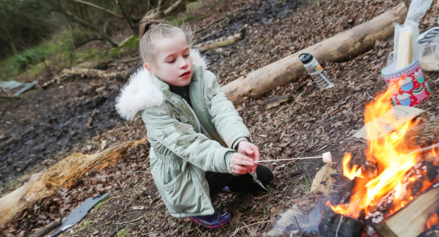 A child toasting a marshmallow over a small fire at Middle Spernal