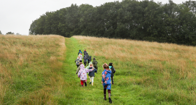 A group of children running uphill towards the woodland at Middle Spernal