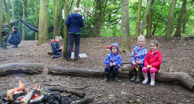 A group of children sat on a log in the woodland at Middle Spernal