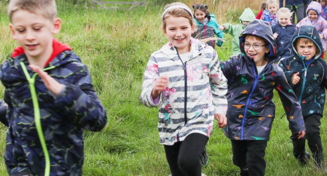 A group of children running through the open grassland at Middle Spernal