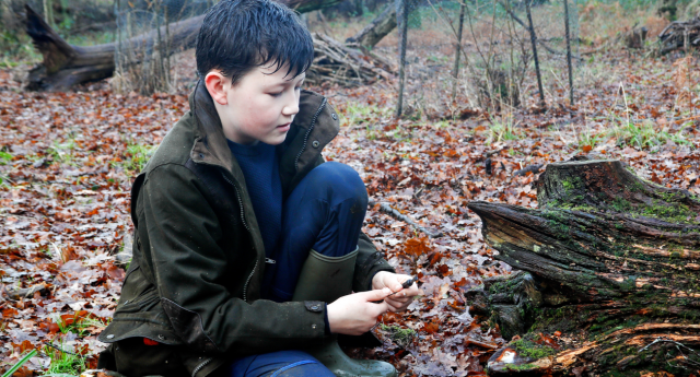 A Young Forester using tools whilst crouched down by a tree log at Middle Spernal