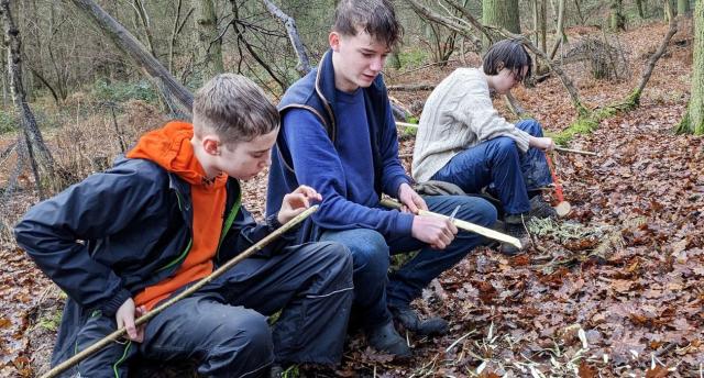 Young people taking part in a bushcraft activity in the Heart of England Forest.