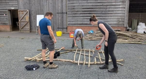 Volunteers constructing a palisade fence from Hazel timber 
